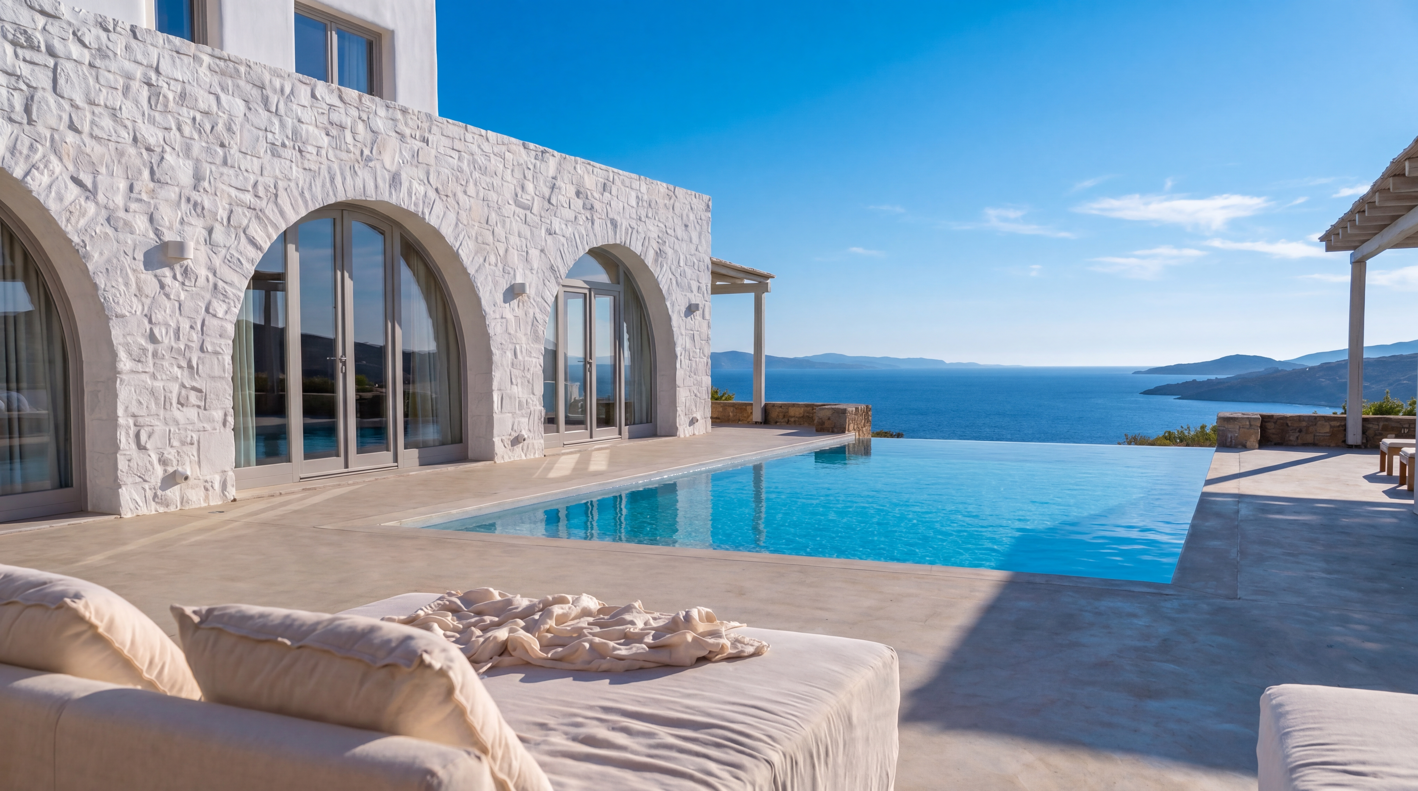 Luxury Cycladic villa with infinity pool at golden hour, overlooking the Aegean sea