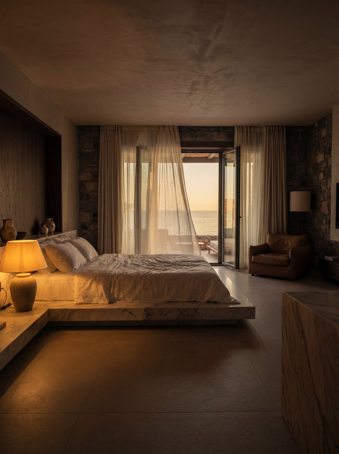 Moody boutique hotel suite at dusk with sea-view balcony and flowing curtains
